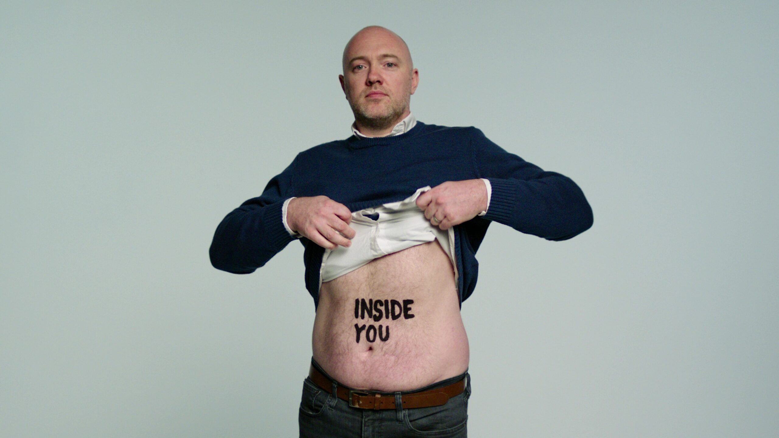 Living kidney donor James lifting his top to reveal the words 'inside you' on his stomach