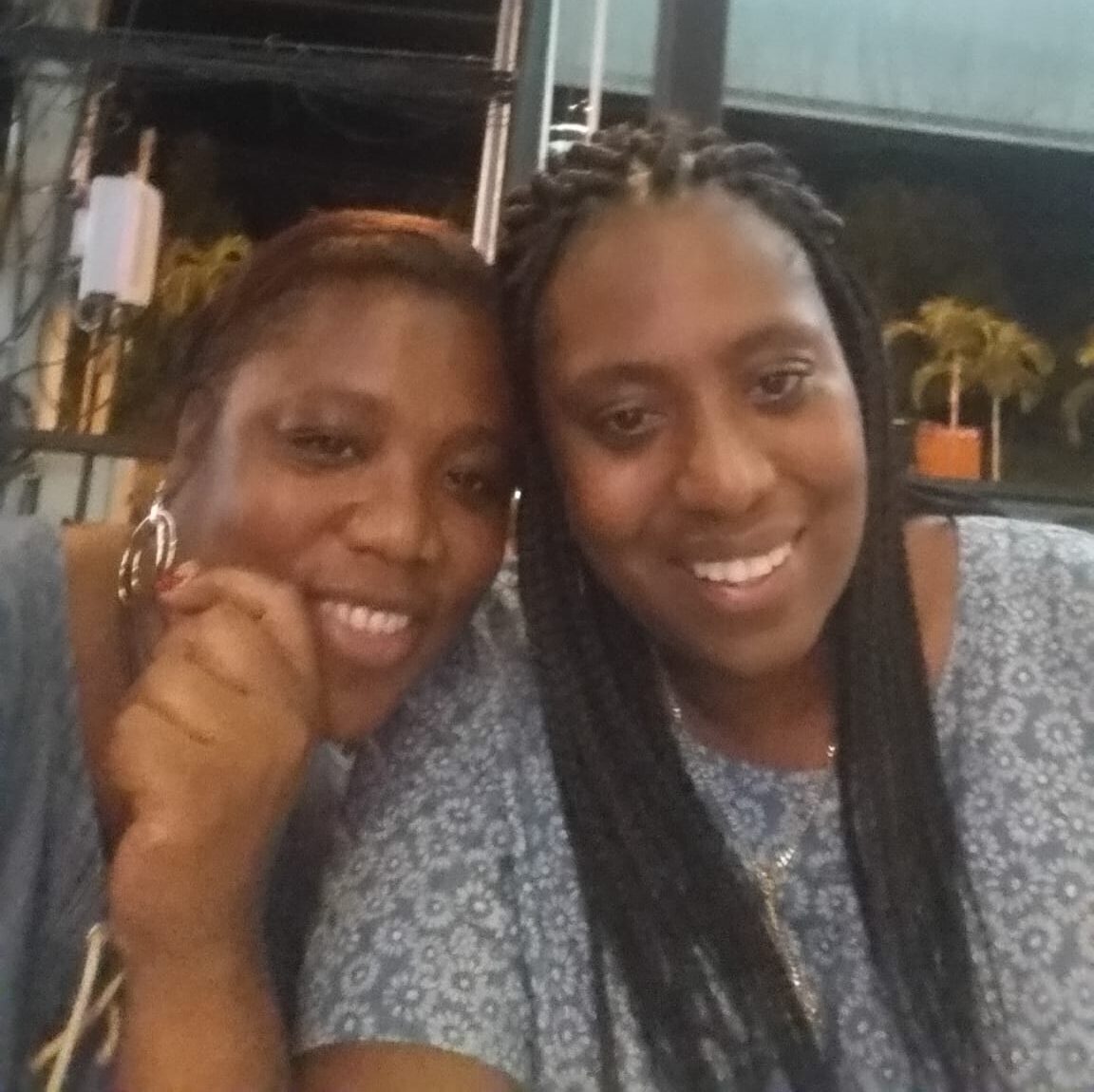 Living kidney donor Maria alongside her sister and kidney recipient Ali. Both are leaning into each other and smiling widely for the camera. Ali is wearing a light blue top with white flowers on it.