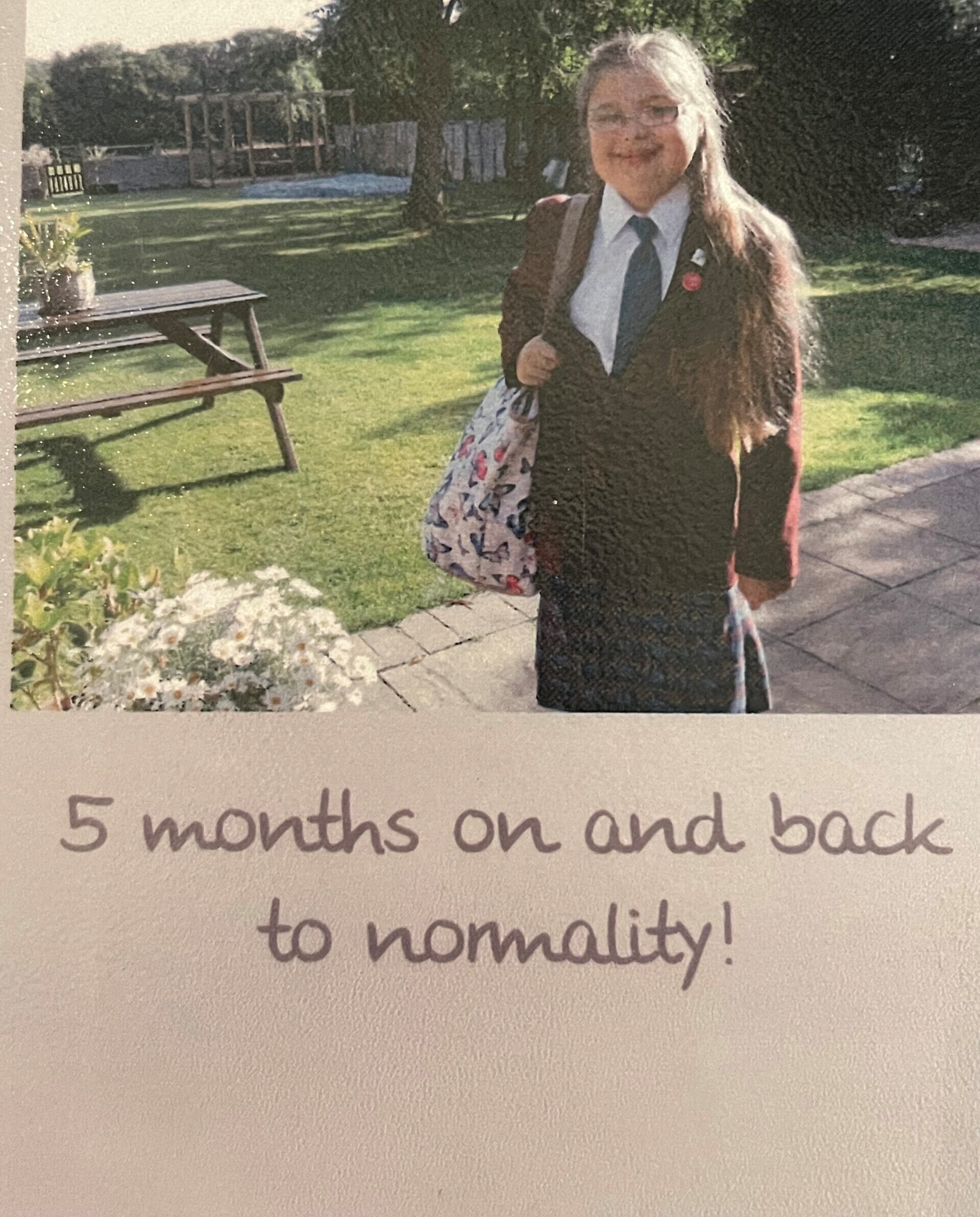 An image of Matt's teenage daughter and kidney recipient, dressed in her school uniform in her garden smiling widely for the camera. Underneath the picture are the words '5 months on and back to normality!'