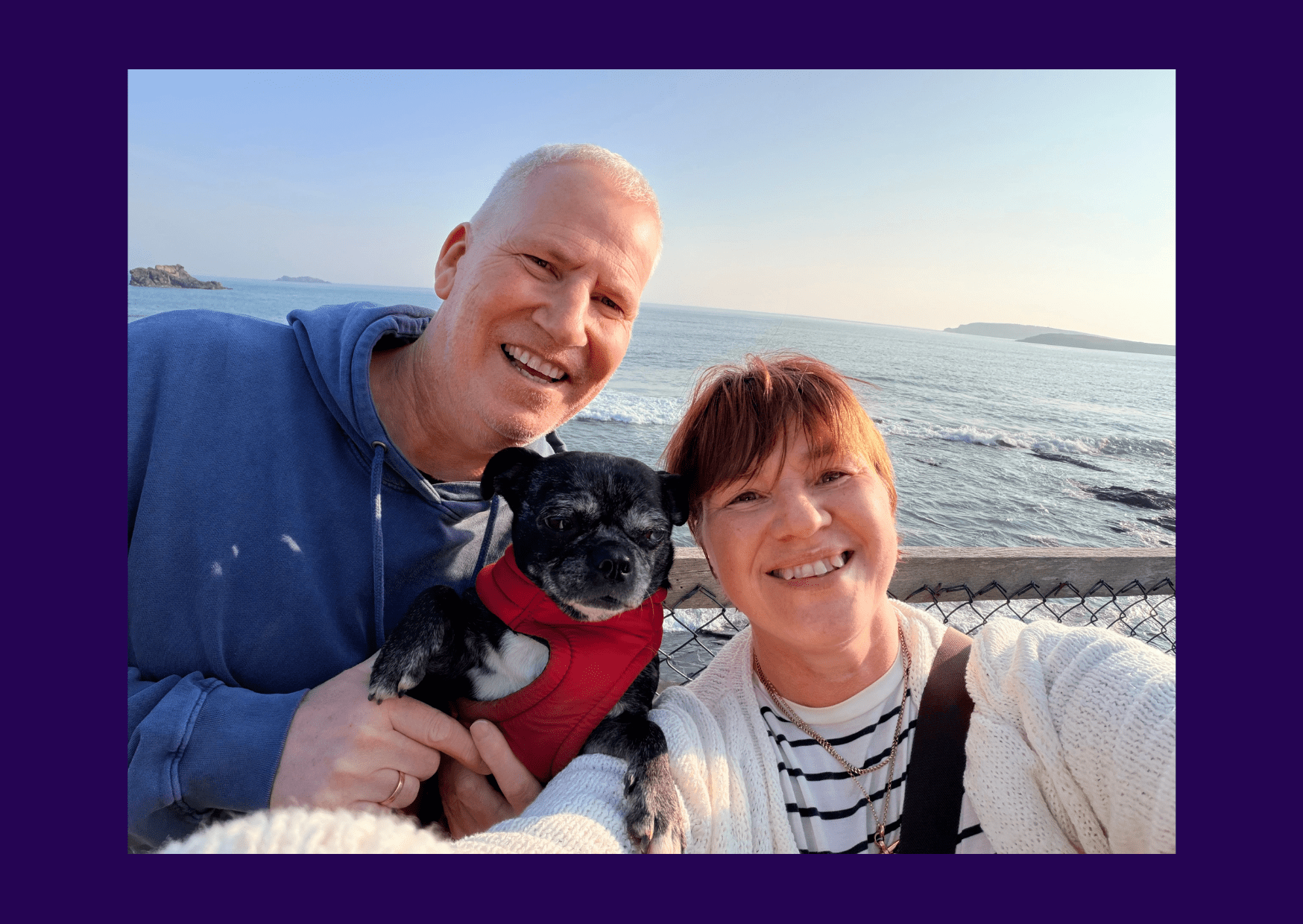 Living kidney donor Stephen taking a selfie on a boat alongside his wife and dog. they are all looking at the camera and smiling, in front of a calm sea and clear blue sky.