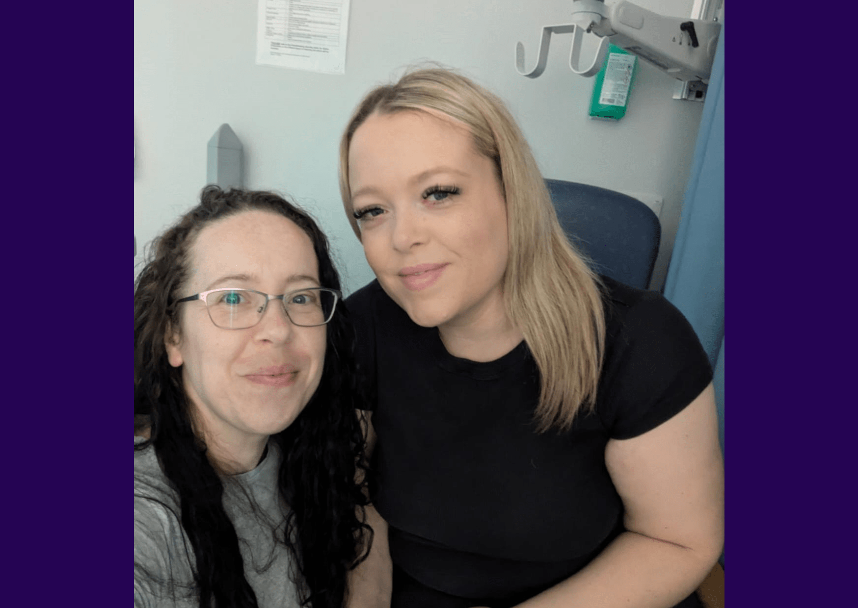 Image of kidney recipient Holly sitting on a hospital chair, wearing a black top and smiling for the camera.