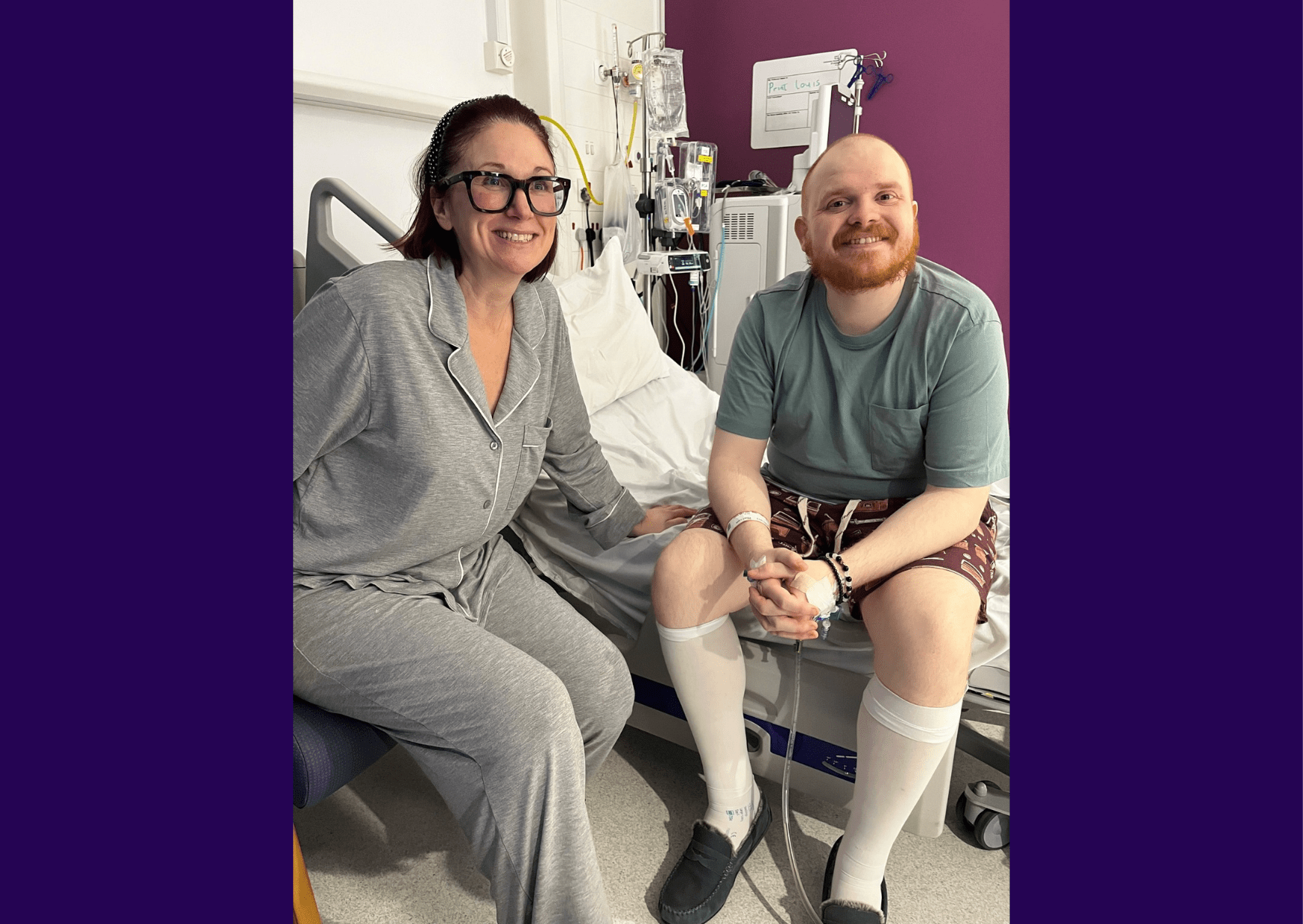 Image of living kidney donor Jo and her nephew Louis in hospital together. Louis is sitting on the edge of a hospital bed while Jo is on a chair next to him. She is wearing a grey gown while he is wearing a plain green top and shorts. Both are smiling at the camera.